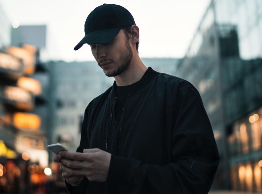 A white male using a phone in an urban setting.